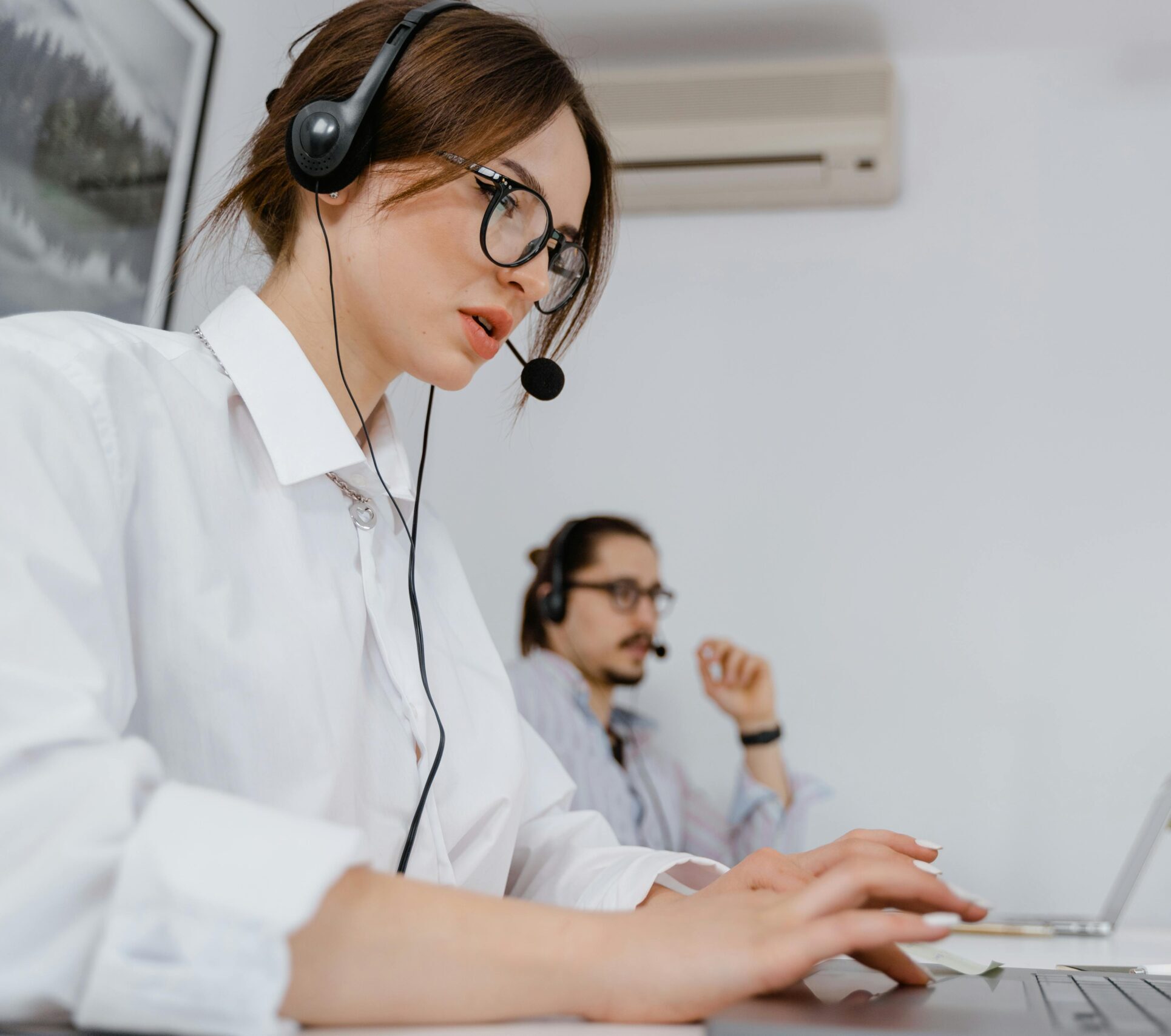 Focused customer support professionals working in a modern office with headsets and laptops.