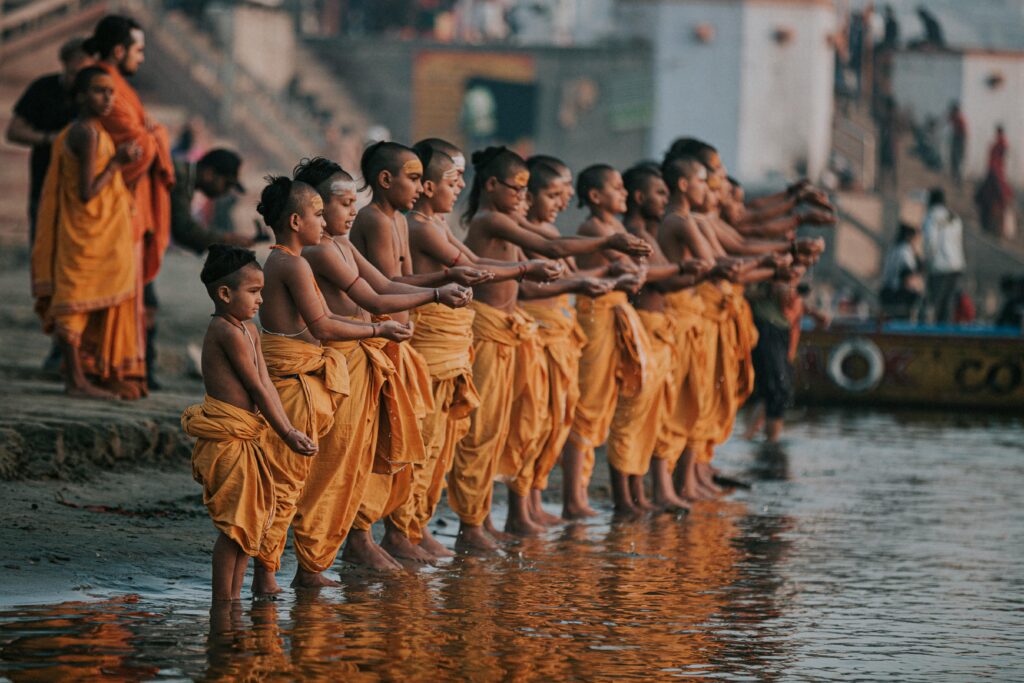 Young Hindu monks performing a ritual on the Ganges River in Varanasi, India during a serene day.